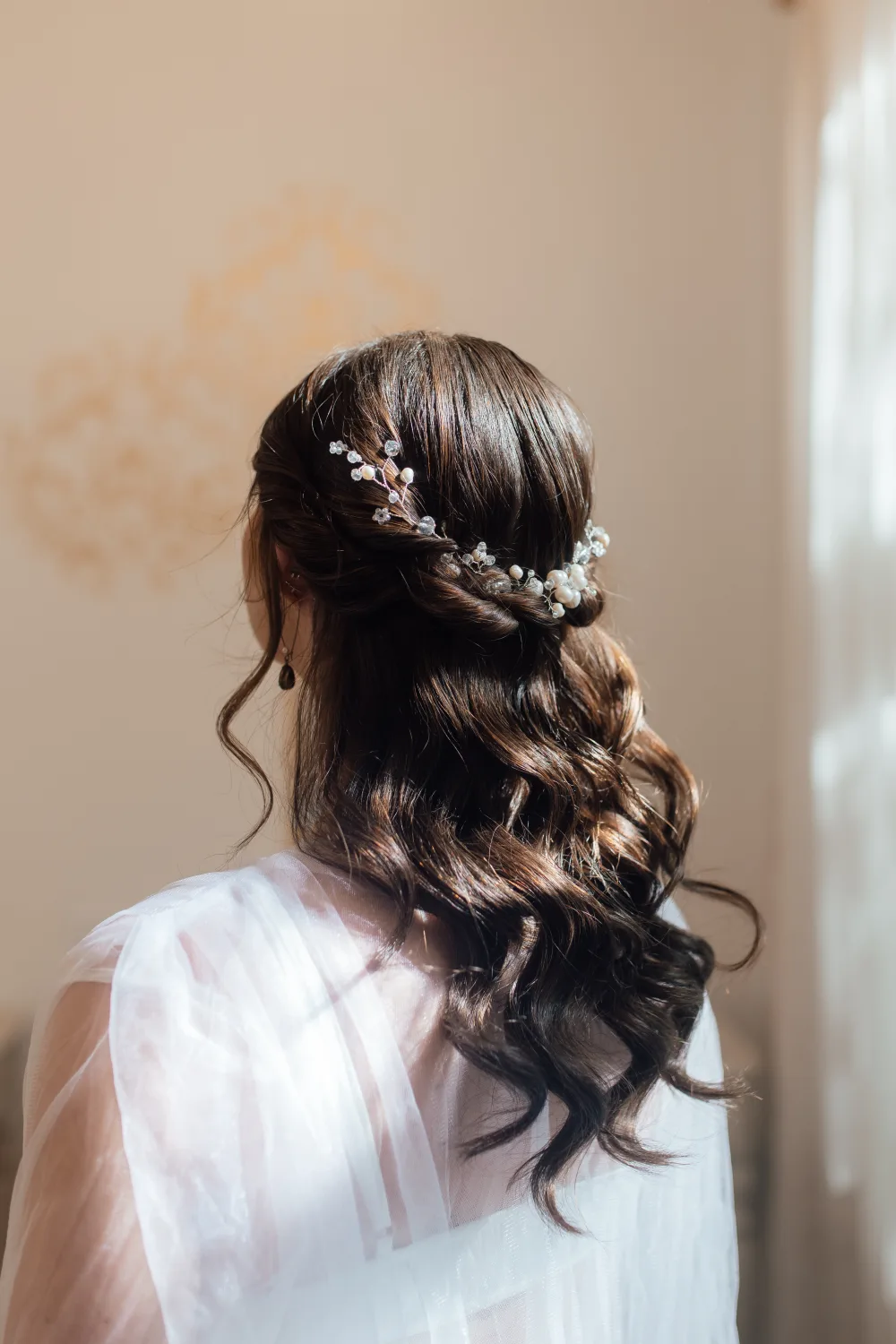 Half-up bridal hairstyle with waves and delicate hair accessories